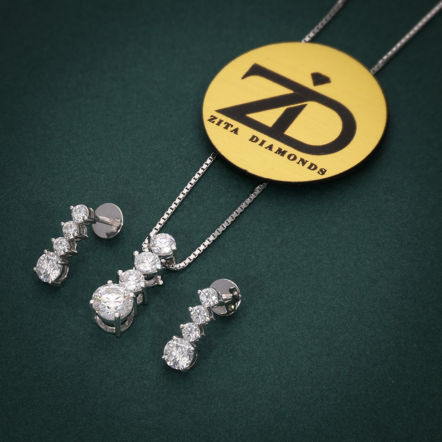 Diamond jewelry set with necklace and earrings on a green background, featuring Zita Diamonds branding.