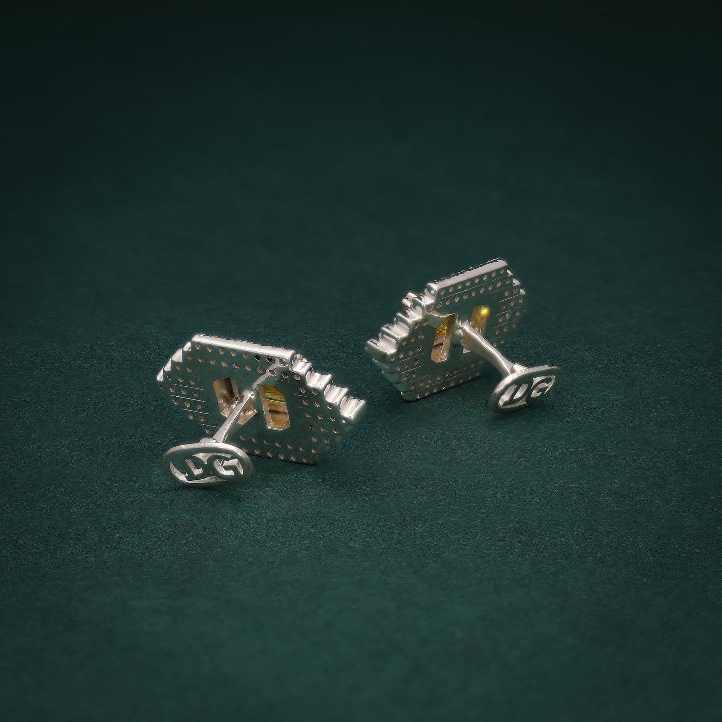 Pair of silver cufflinks with a stunning arrangement of lab-grown diamonds and yellow accents on a green background