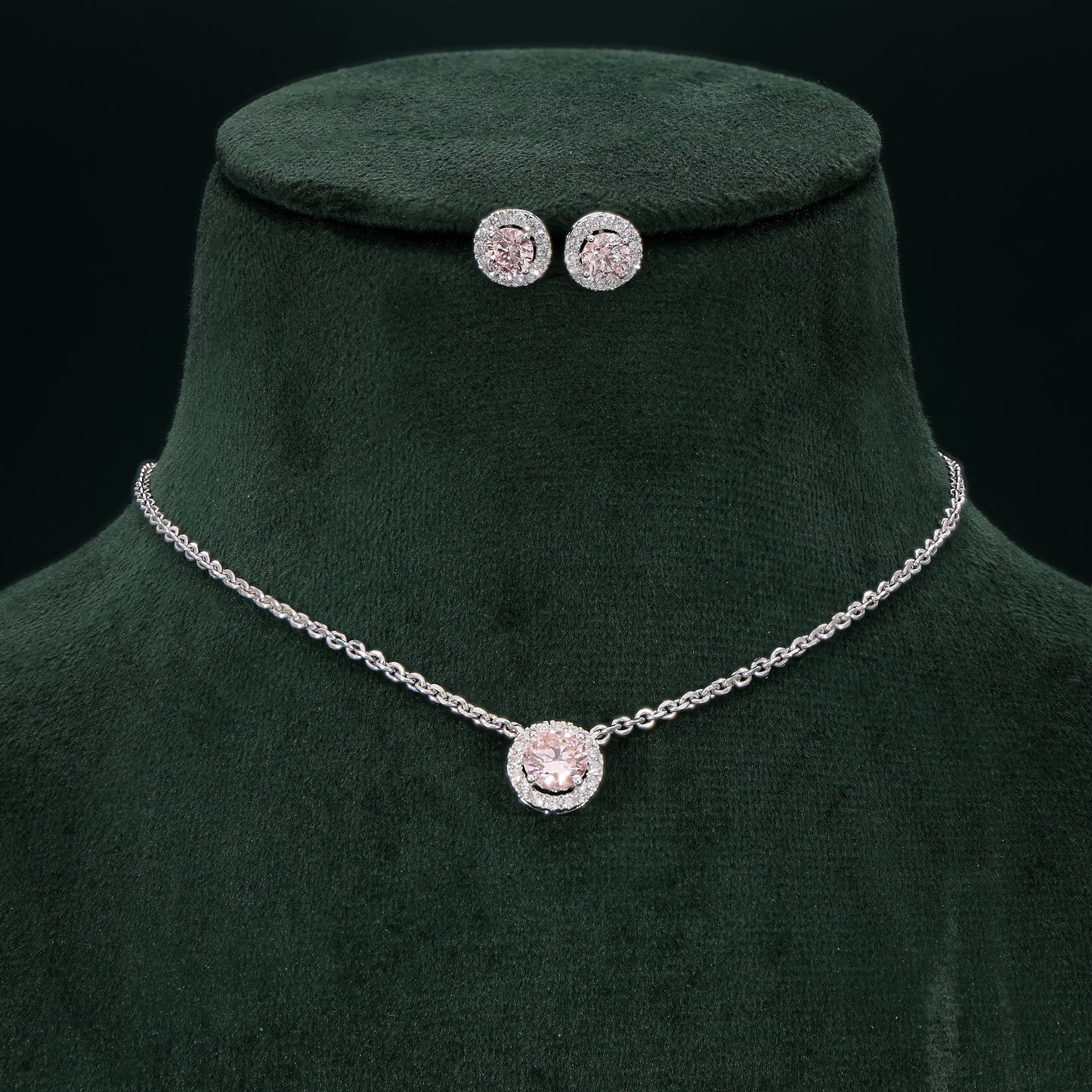 Jewelry set with necklace and earrings on a green velvet stand against a black background