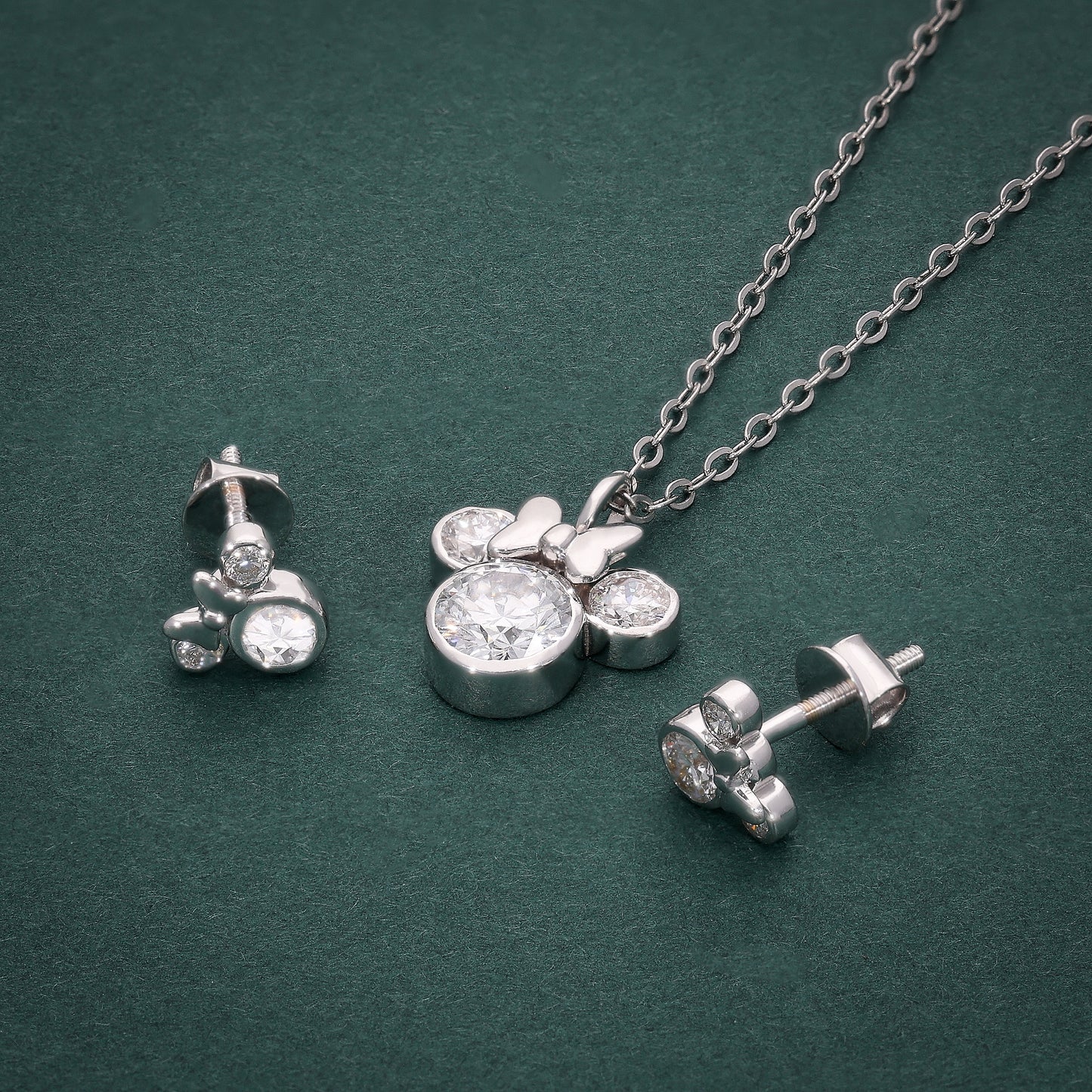 White gold necklace and earrings with Mickey Mouse–shaped design, featuring lab-grown diamonds, displayed on a dark green background.