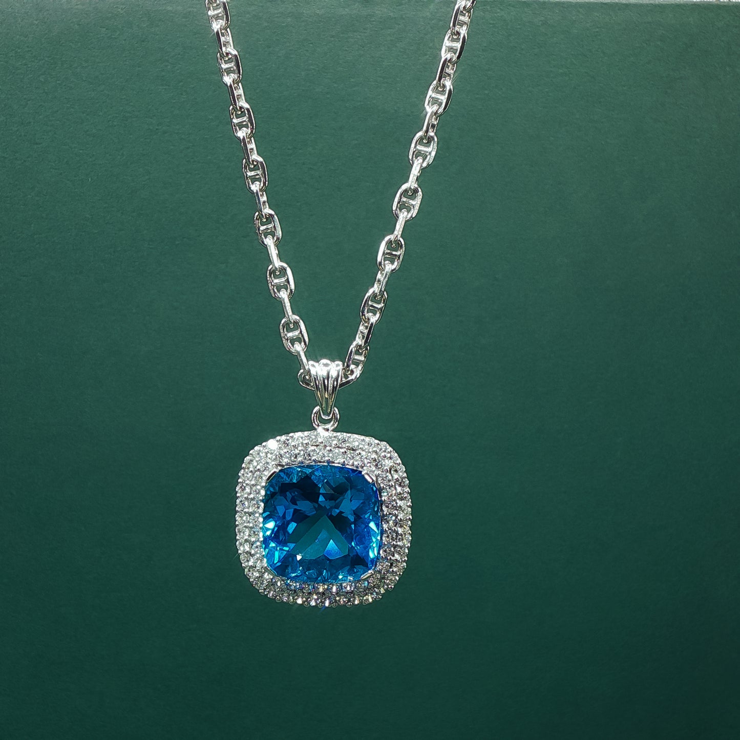 Silver necklace with a blue gemstone pendant on a green background