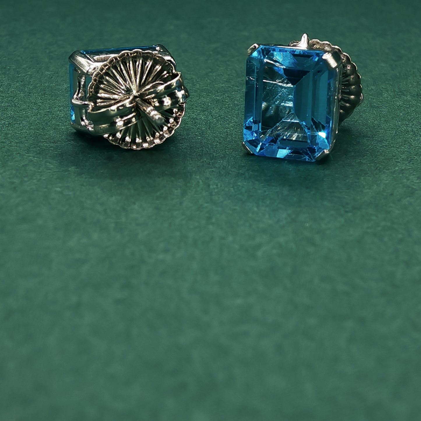 Pair of silver earrings with blue gemstones on a green background