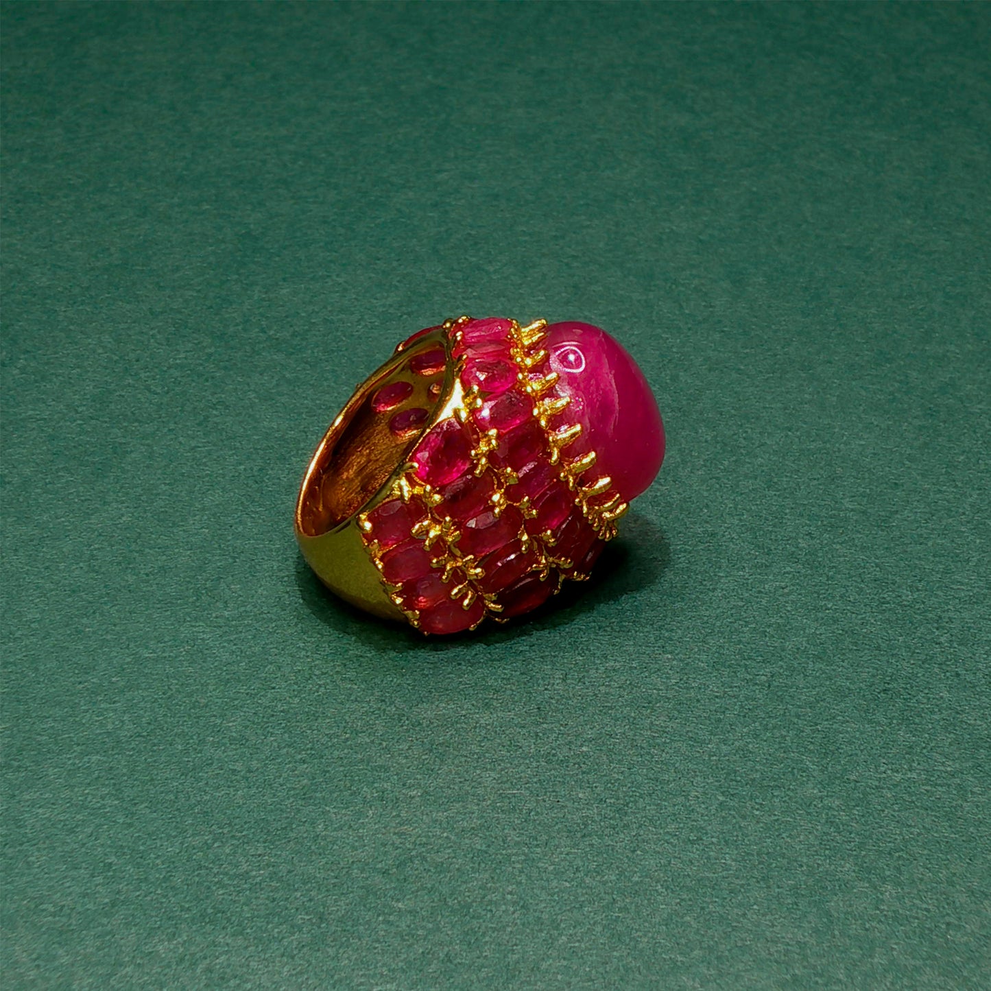 Pink gemstone ring with gold setting on a green background
