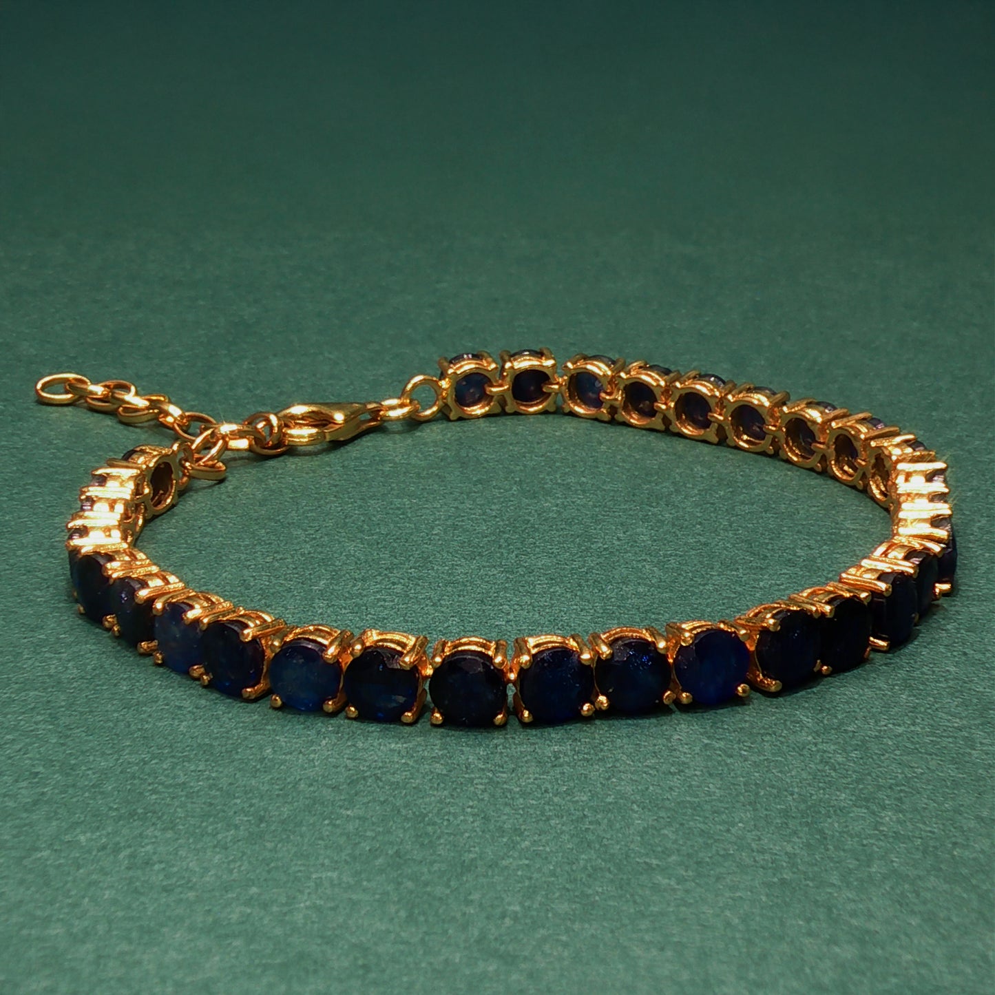 Gold bracelet with blue stones on a green background