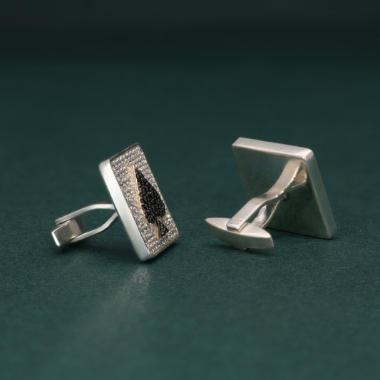 Pair of lab grown diamond cufflinks with spade symbol design on a dark green background