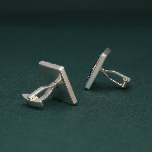 Pair of lab grown diamond cufflinks with spade symbol design on a dark green background