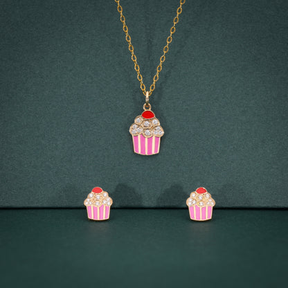 Cupcake-themed necklace and earrings on a green background