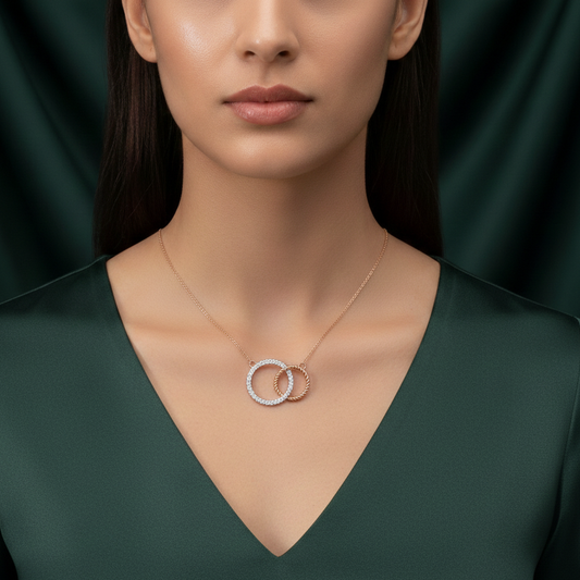 Woman wearing a necklace with interlocking rings against a dark green background