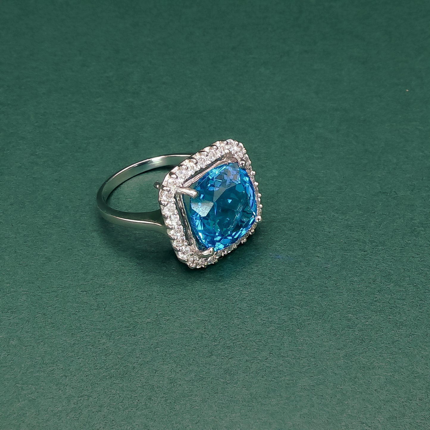 Silver ring with a blue gemstone on a green background