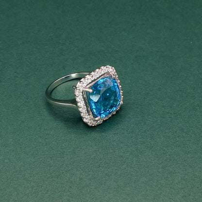 Silver ring with a blue gemstone on a green background
