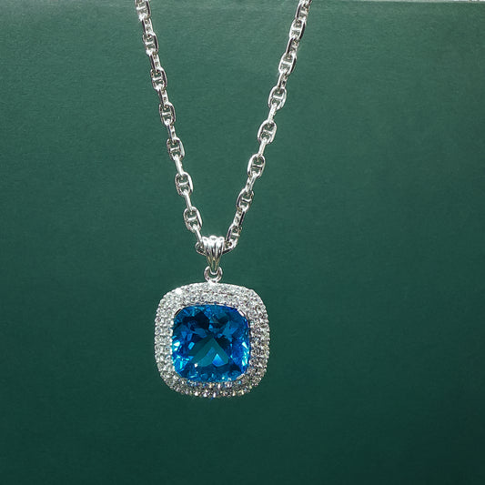 Silver necklace with a blue gemstone pendant on a green background

