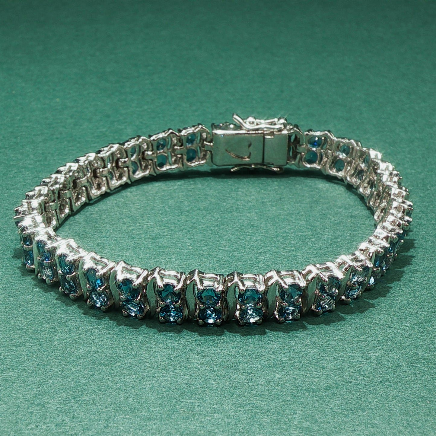 Silver bracelet with blue gemstones on a green background