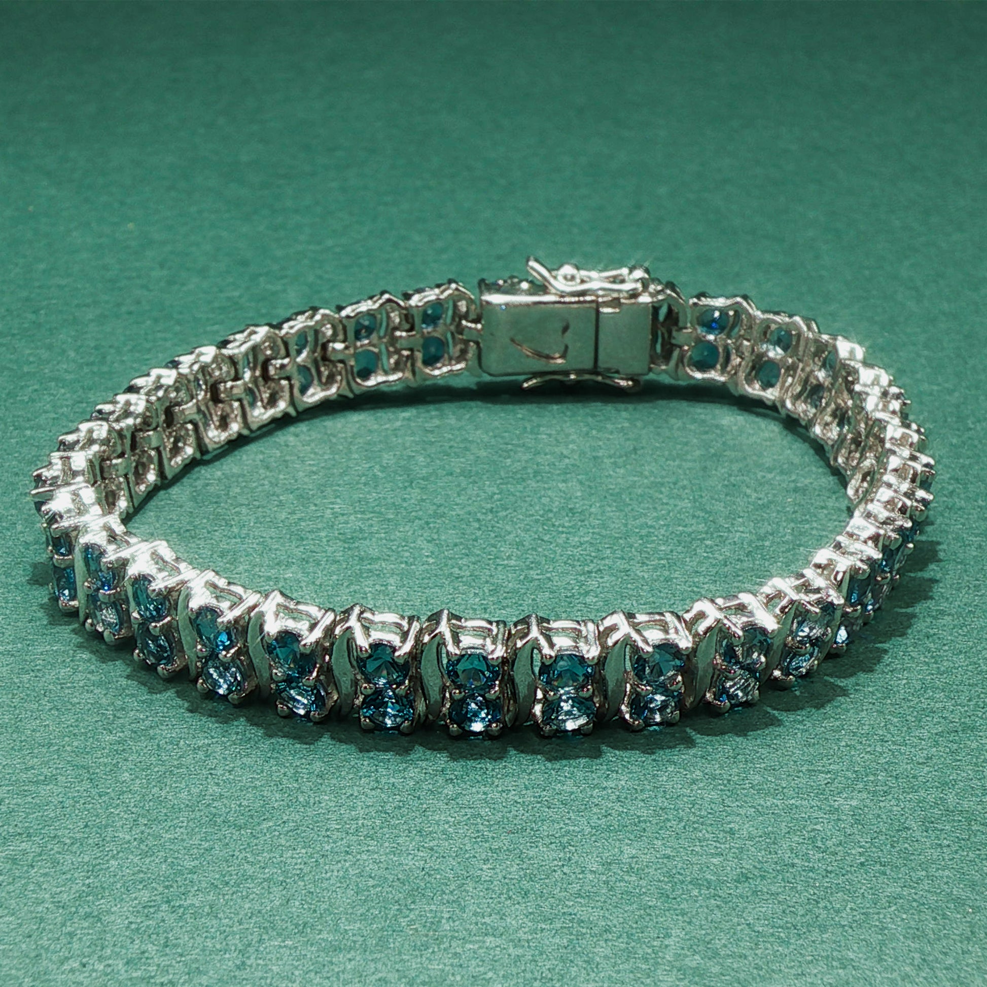 Silver bracelet with blue gemstones on a green background