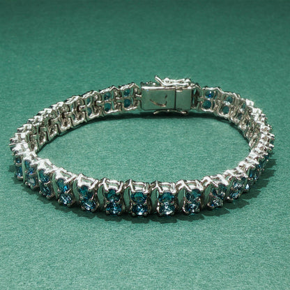 Silver bracelet with blue gemstones on a green background