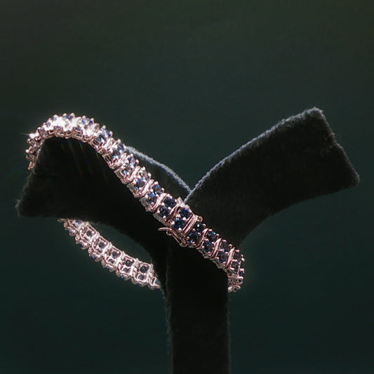 Silver bracelet with blue stones on a black stand against a dark background