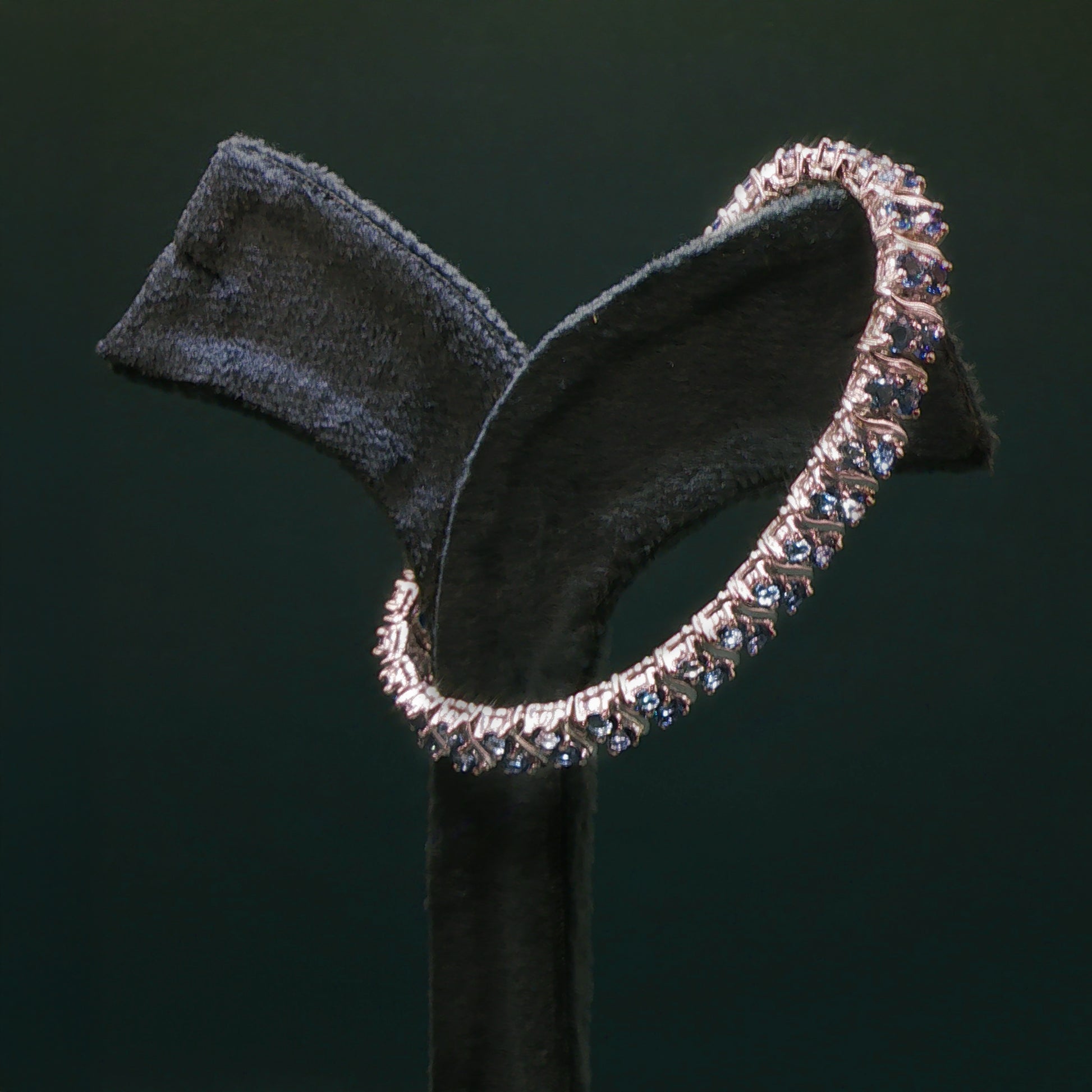 Silver hoop earring on a black stand against a dark background

