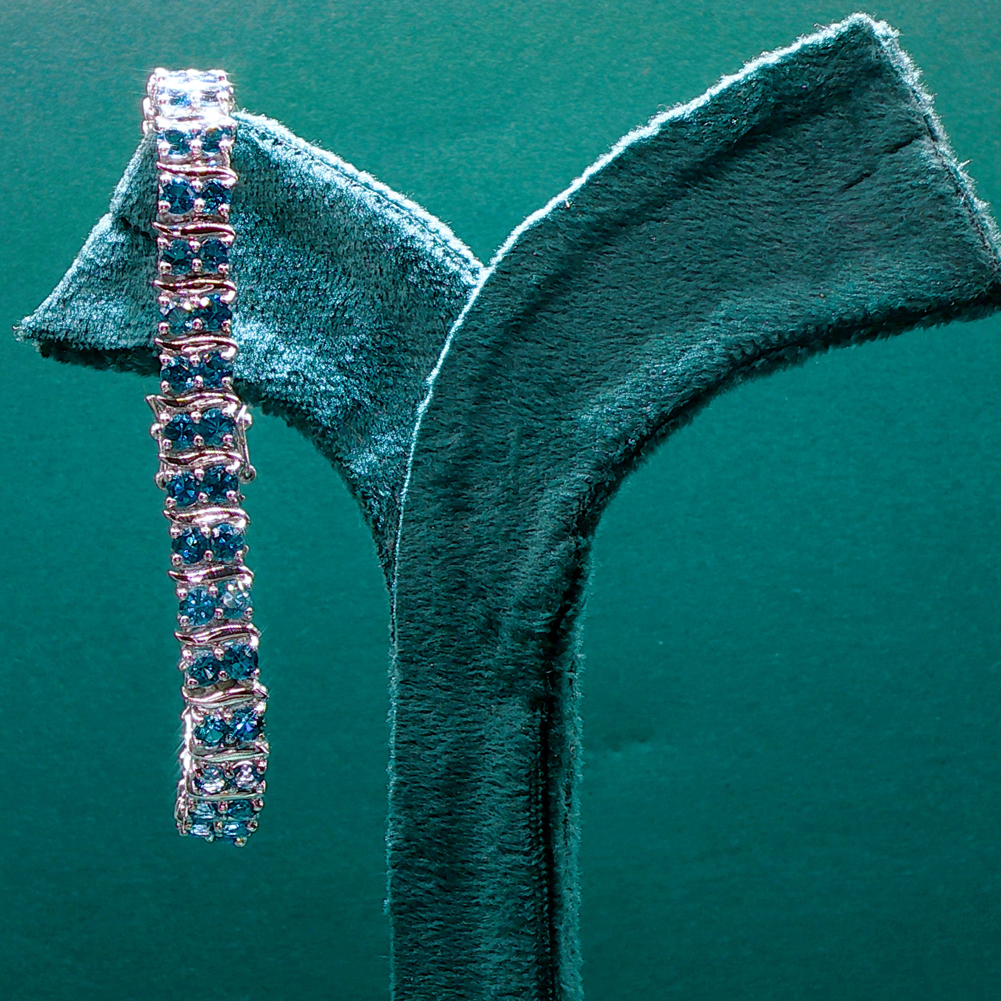 Silver bracelet with blue stones on a green velvet stand