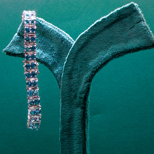 Silver bracelet with blue stones on a green velvet stand