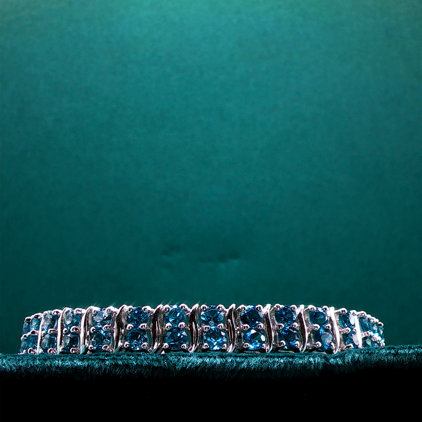 Silver bracelet with blue stones on a teal background