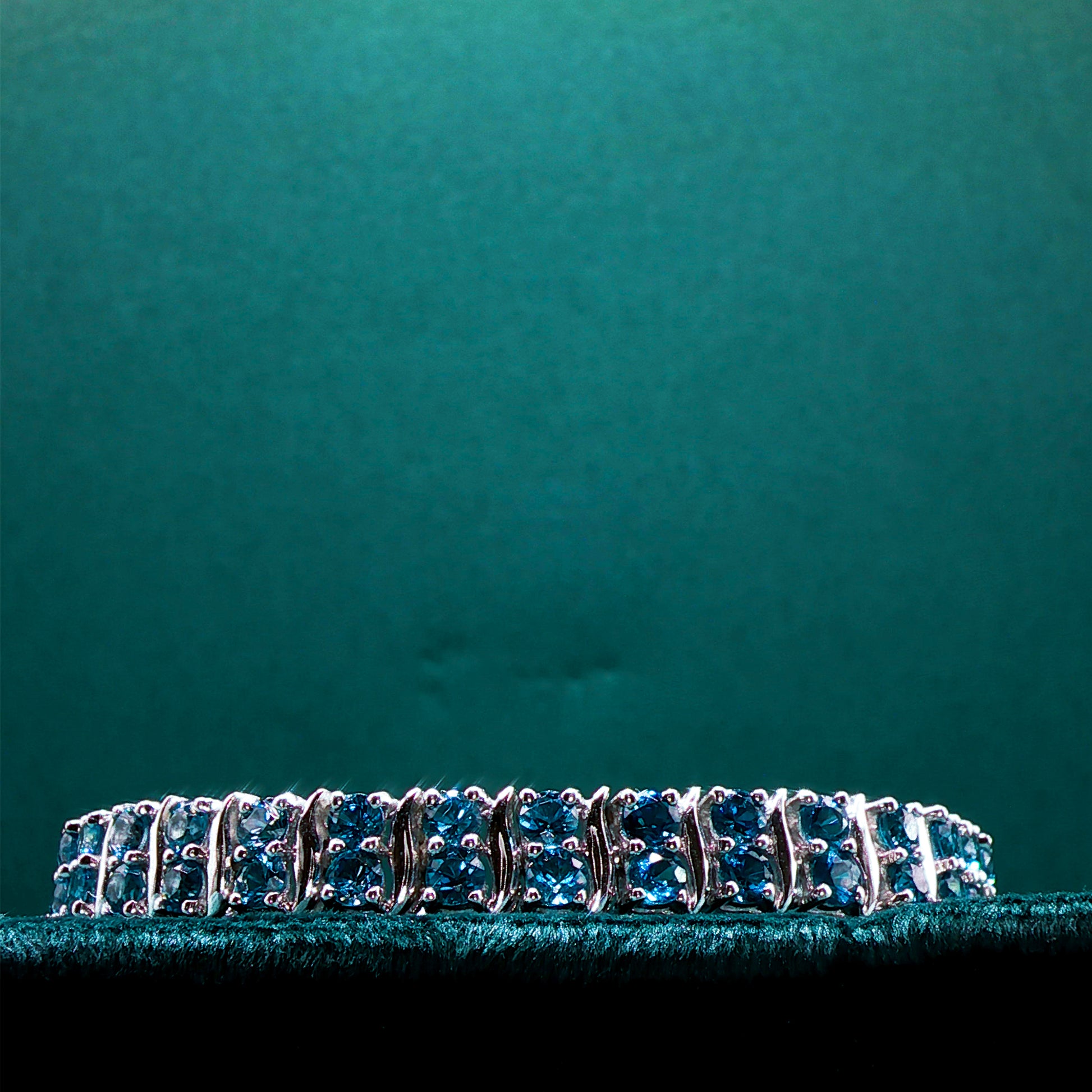 Silver bracelet with blue stones on a teal background