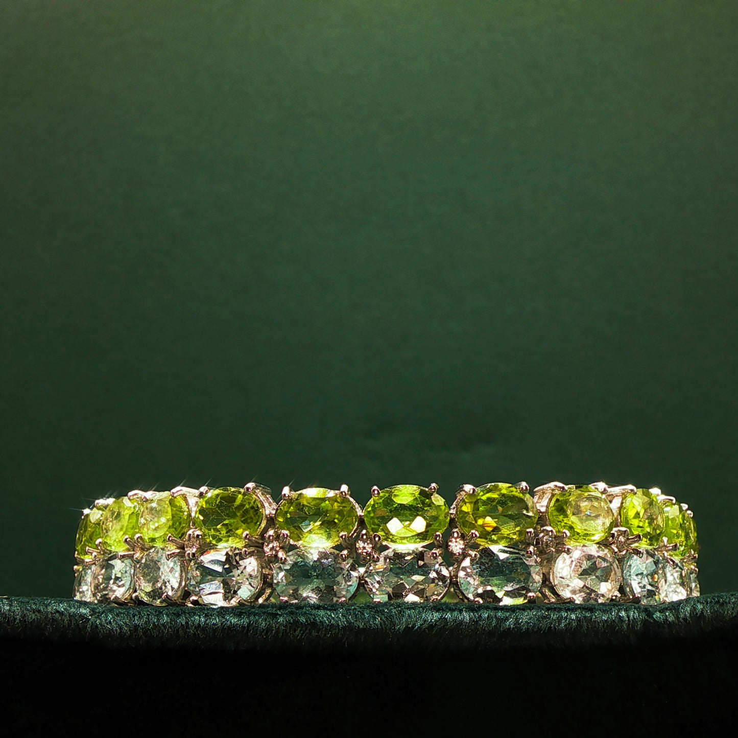 Green gemstone ring with gold setting on a dark green background

