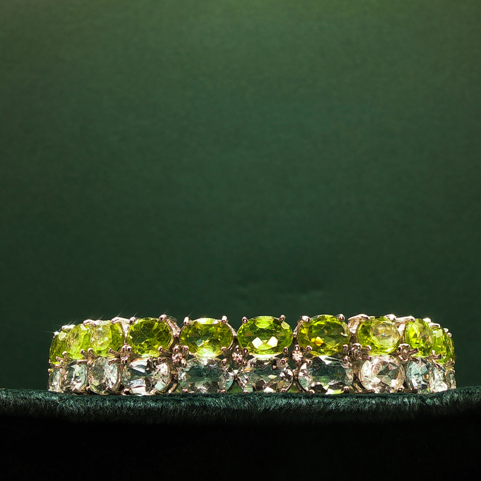 Green gemstone ring with gold setting on a dark green background

