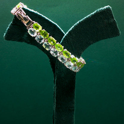 Bracelet with green gemstones on a green stand against a green background

