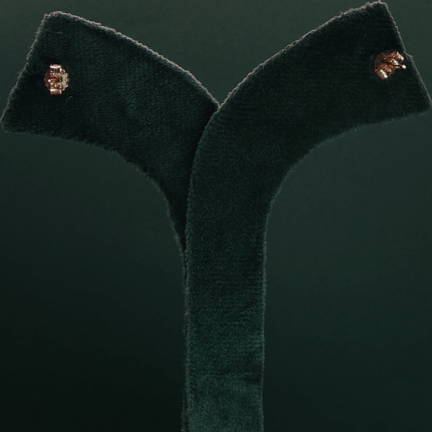 Green velvet garment with gold buttons on a dark green background

