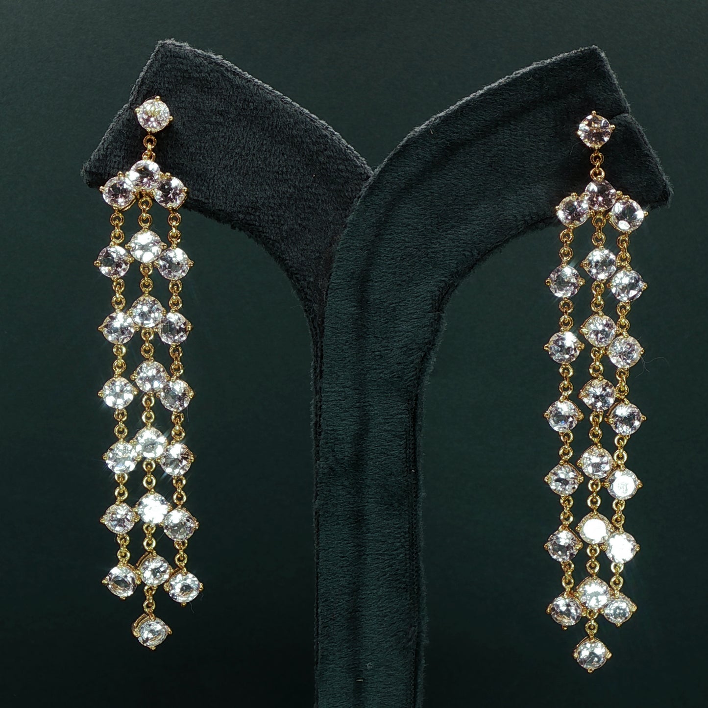 silver diamond earrings with dangling beads on a green velvet stand.

