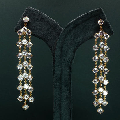 silver diamond earrings with dangling beads on a green velvet stand.

