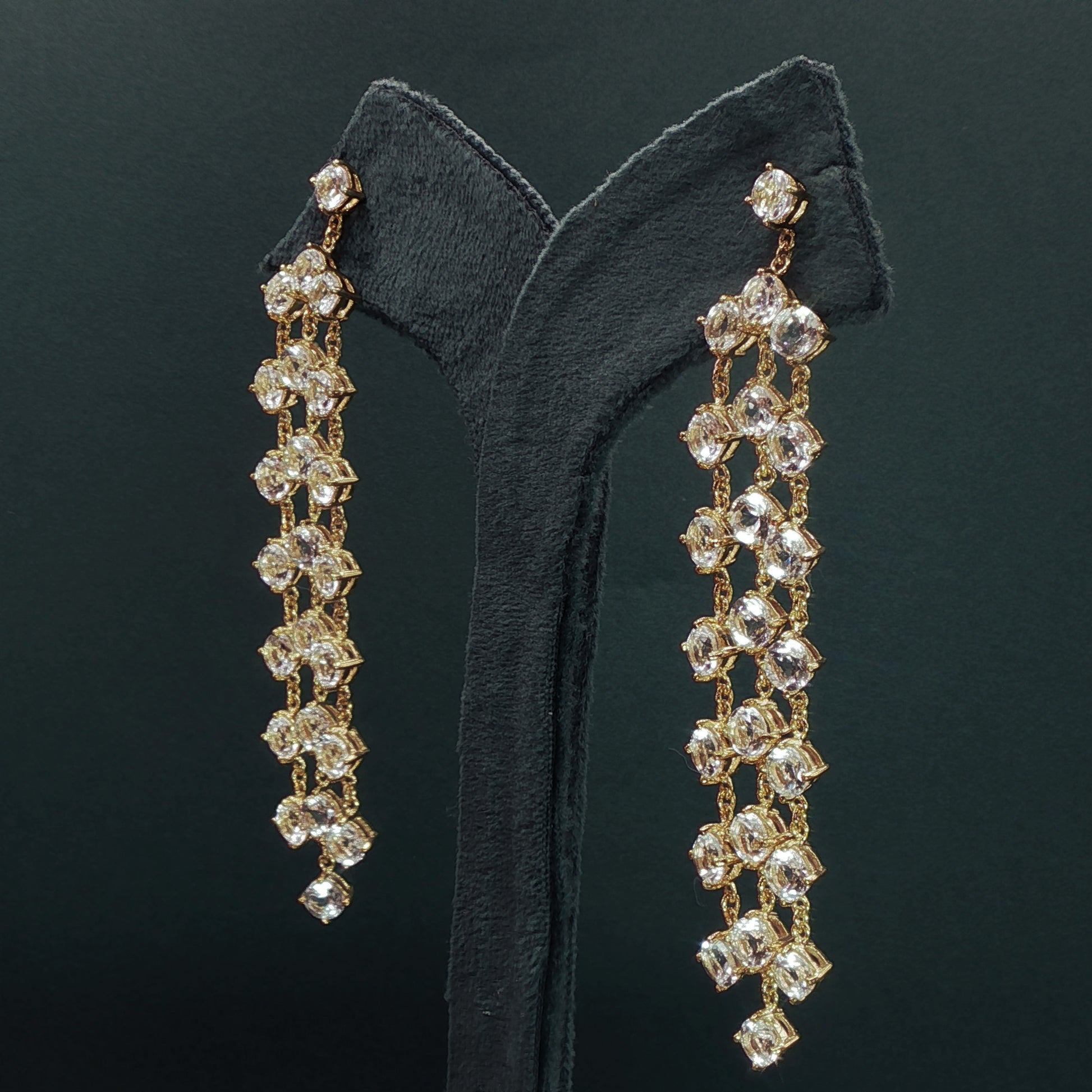 silver earrings with dangling beads on a green velvet stand.

