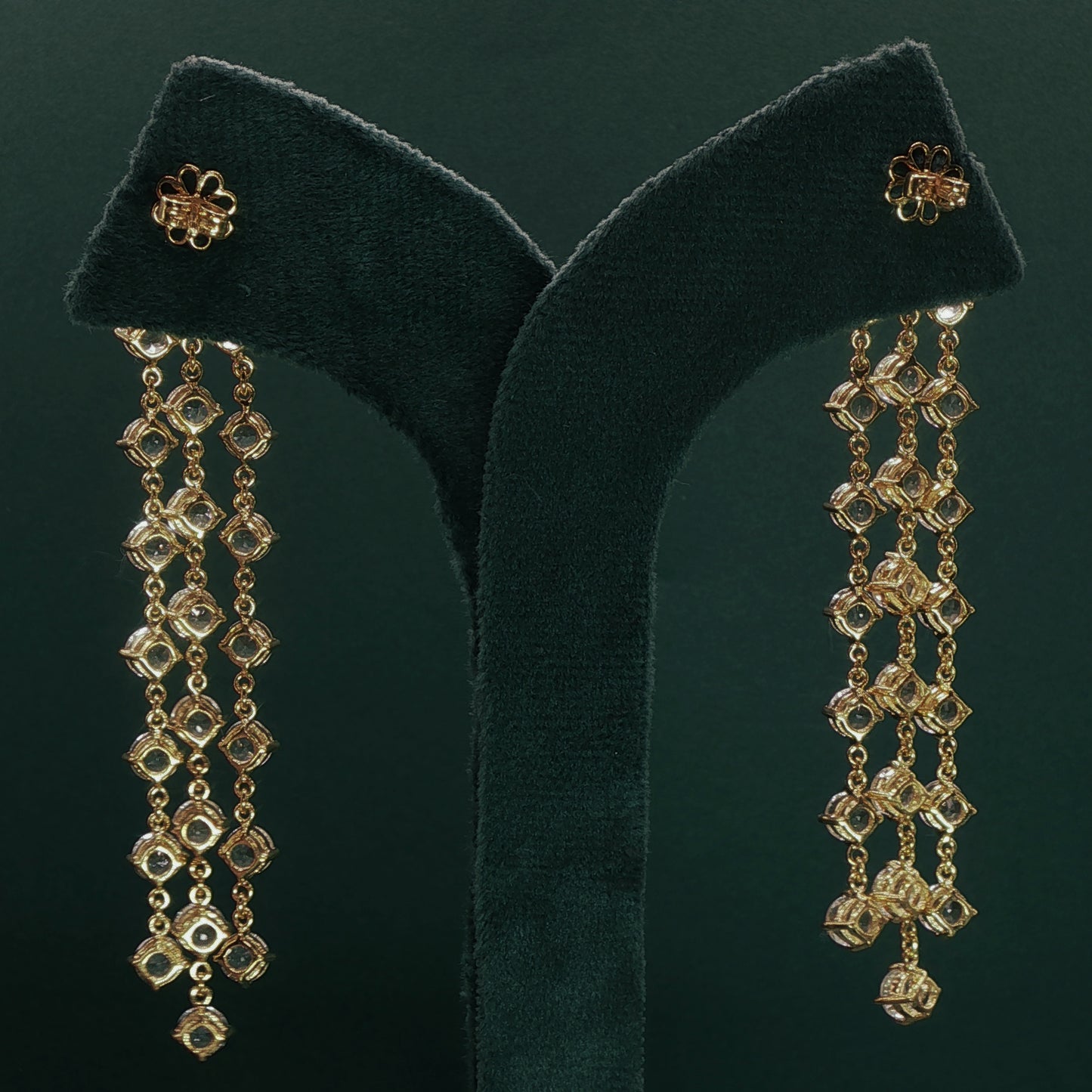 silver earrings with dangling beads on a green velvet stand.

