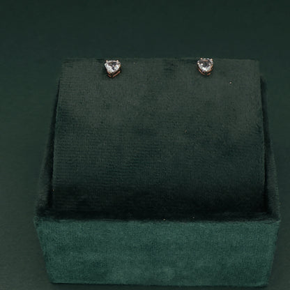 Heart-shaped earrings on a green velvet stand against a dark green background
