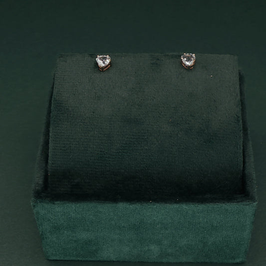 Heart-shaped earrings on a green velvet stand against a dark green background
