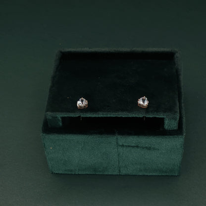 Pair of diamond stud earrings in a green velvet box on a dark background

