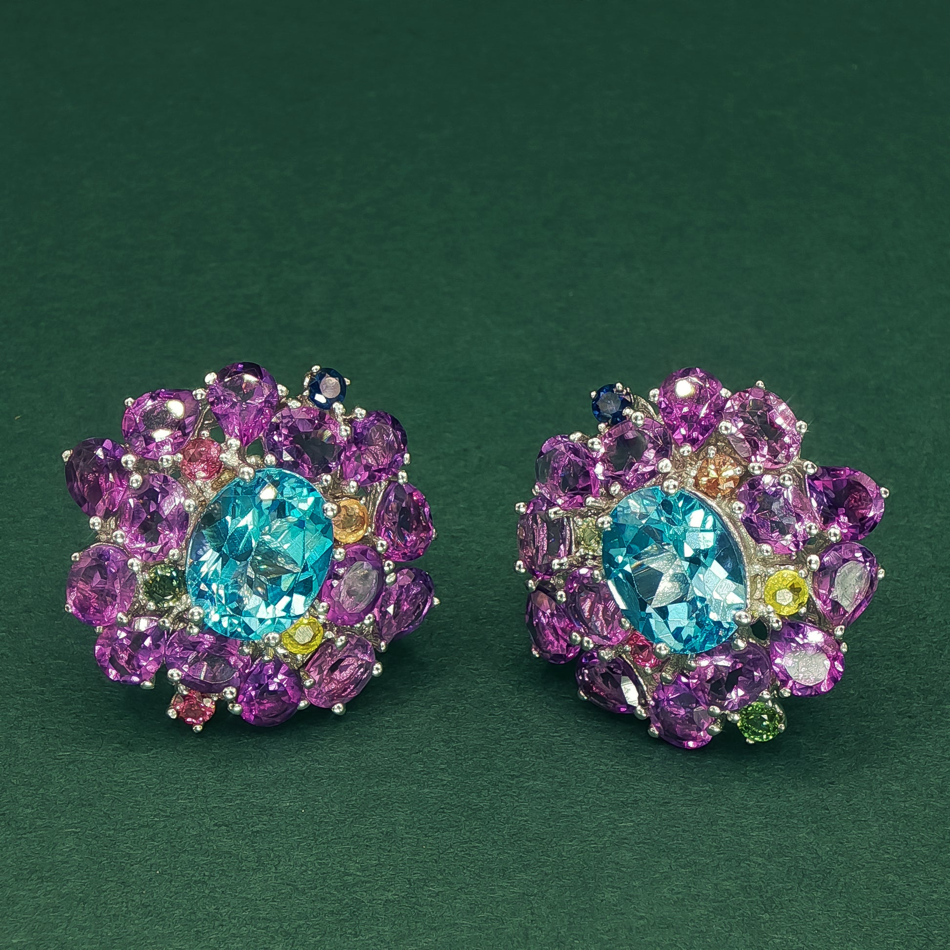 Colorful gemstone earrings on a dark green background

