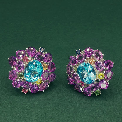 Colorful gemstone earrings on a dark green background

