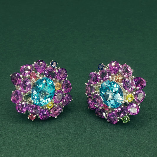 Colorful gemstone earrings on a dark green background

