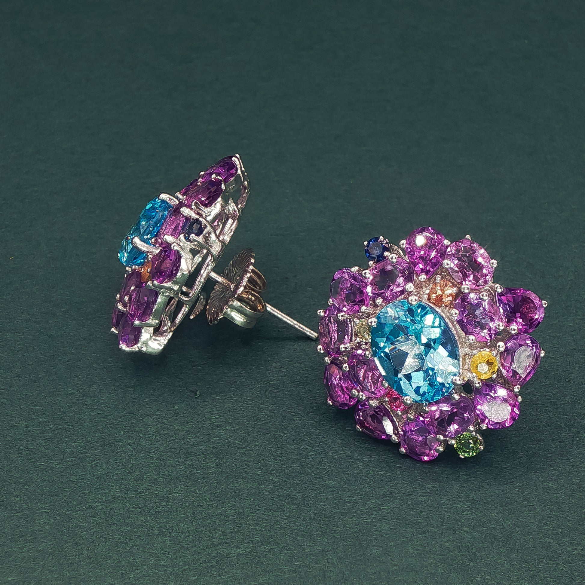 Colorful gemstone earrings on a dark green background

