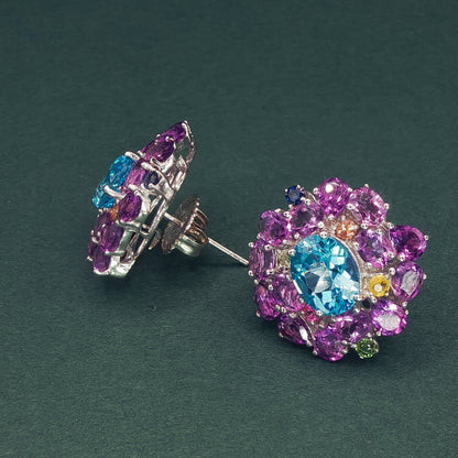 Colorful gemstone earrings on a dark green background

