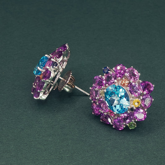 Colorful gemstone earrings on a dark green background

