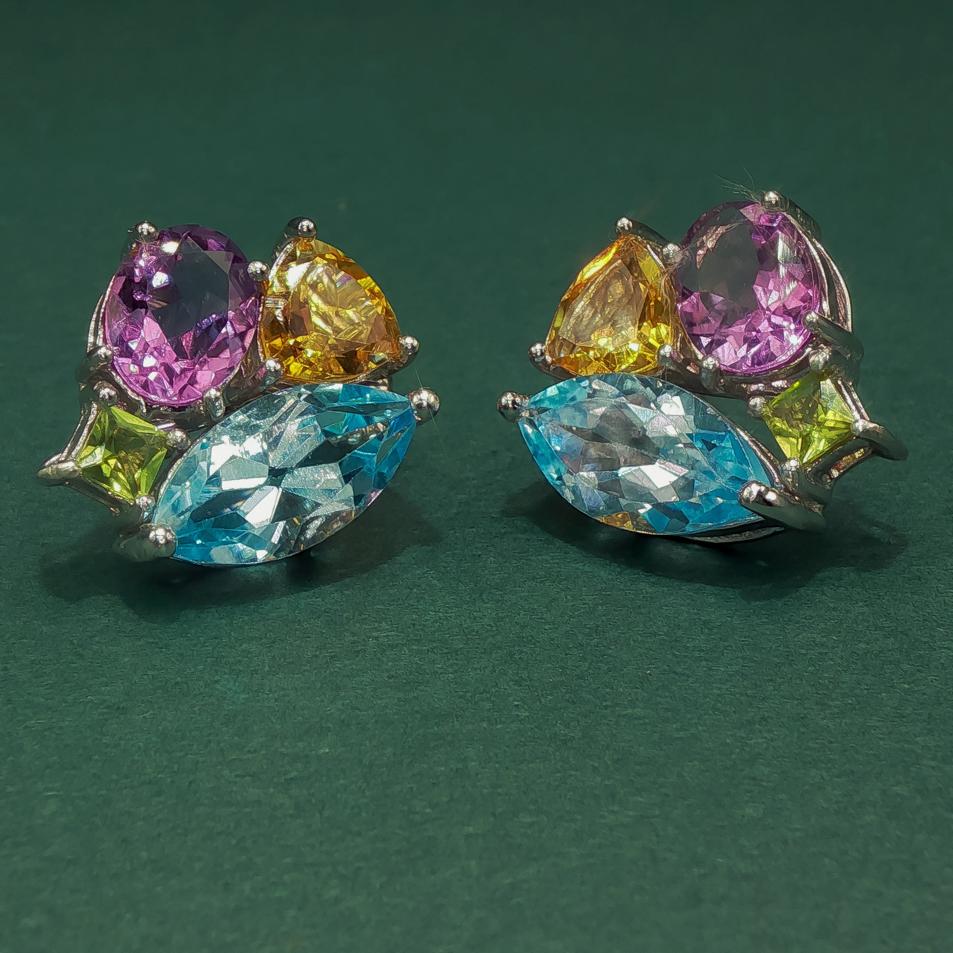 Pair of earrings with multicolored gemstones on a green background