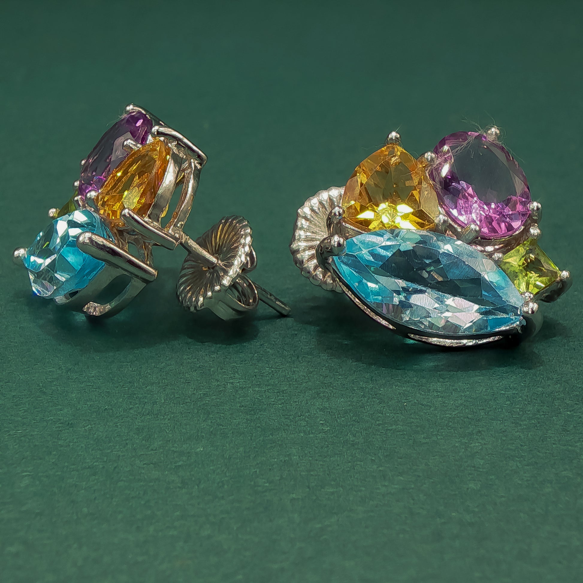 Colorful gemstone earrings on a green background