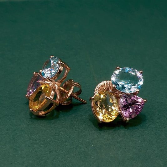 Pair of earrings with multicolored gemstones on a green background
