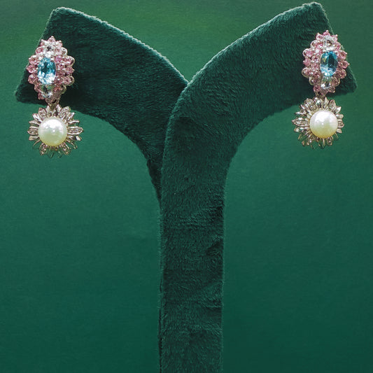 Pair of earrings with gemstones on a green stand against a green background