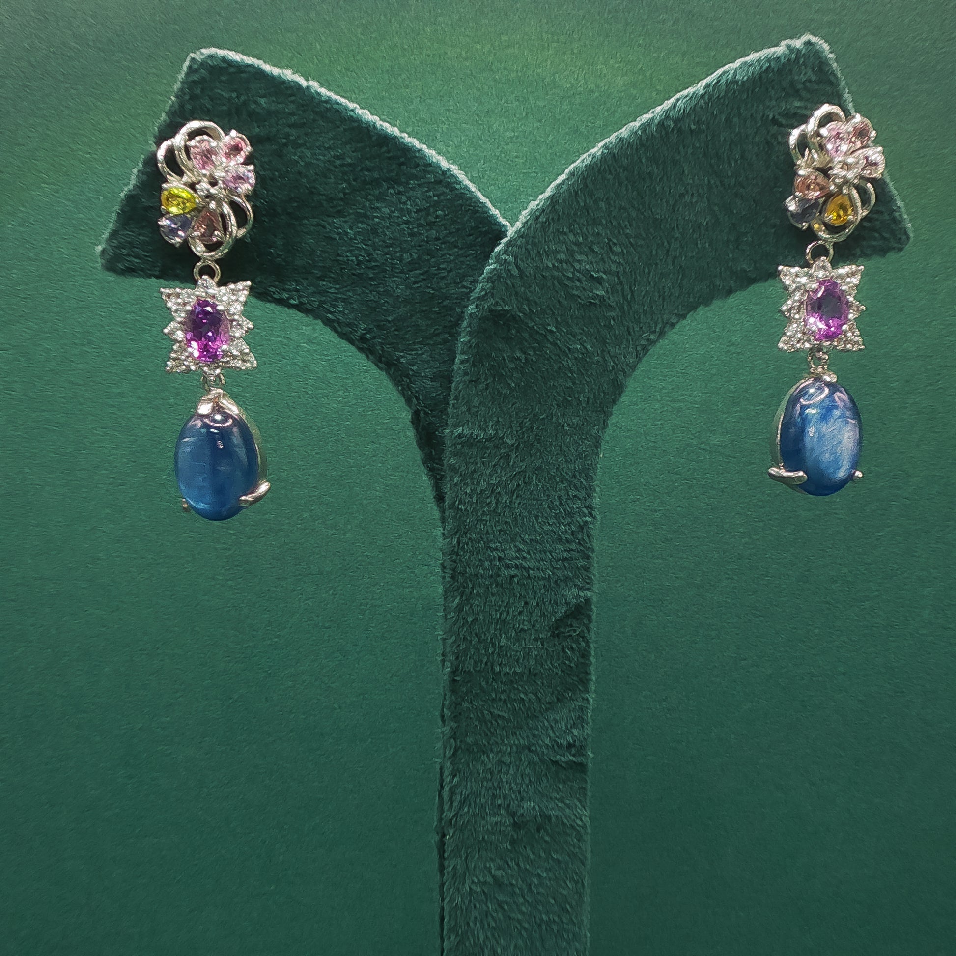 Pair of earrings with gemstones on a green leaf background