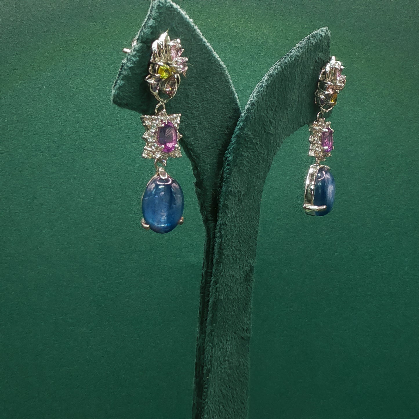 Pair of earrings with gemstones on a green leaf background
