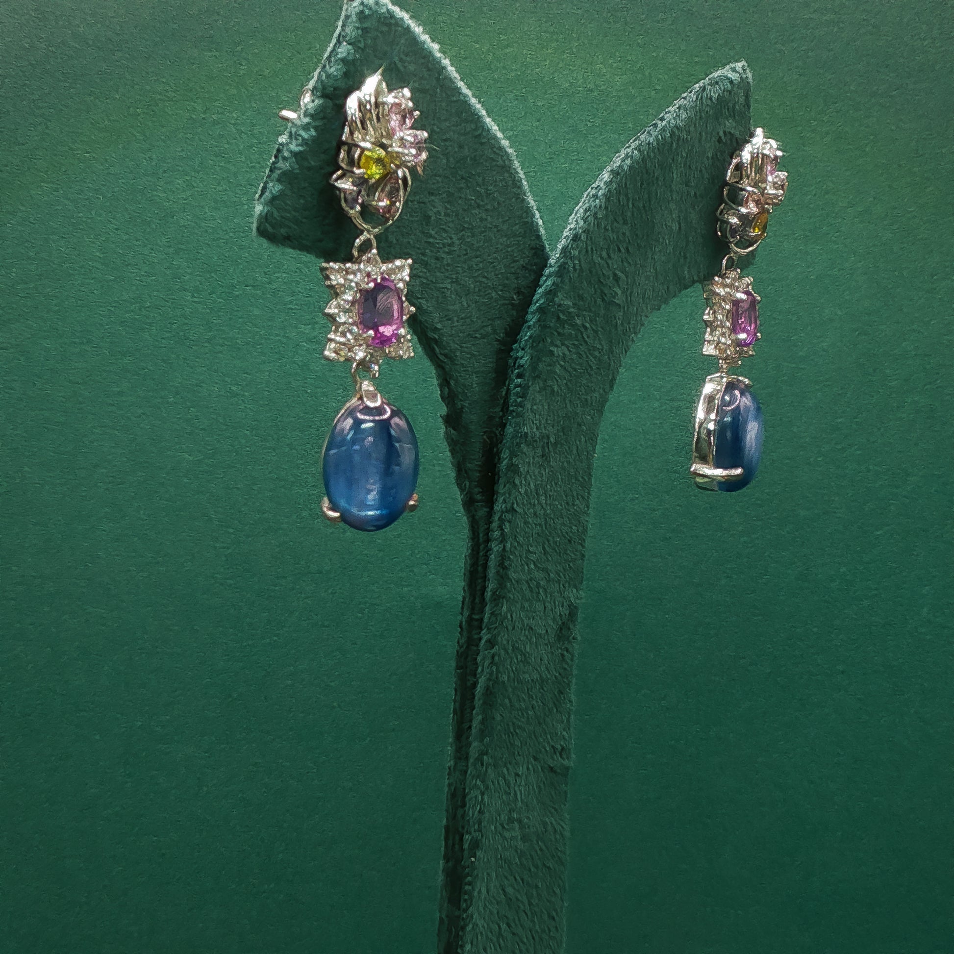 Pair of earrings with gemstones on a green leaf background