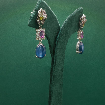 Pair of earrings with gemstones on a green leaf background