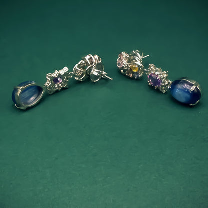 Pair of silver earrings with gemstones on a green background